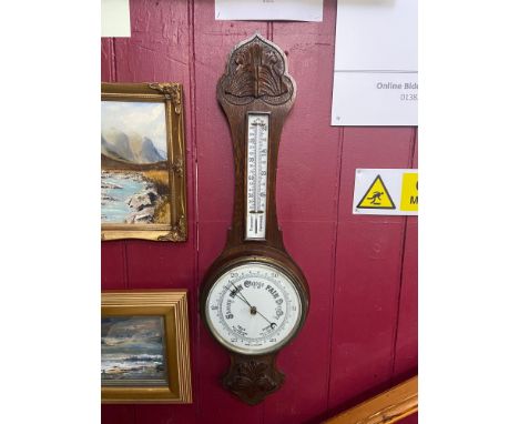 Antique wall barometer and thermometer. Designed in a dark oak case. Enamel white face and contains mercury. 