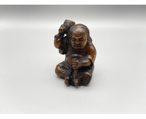 A hand carved Japanese netsuke figurine, depicting a person with a mallet and mouse Signed by the artist. [4.5cm height] 