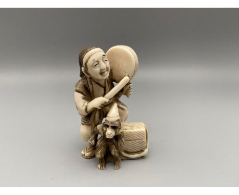 A Meiji Period ivory carved Japanese netsuke of a man beating a drum and his monkey dancing. Signed to the base by the artist