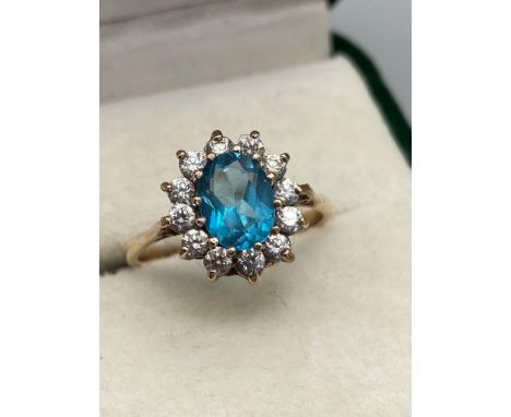 A Ladies 9ct gold ring set with an aquamarine stone off set by a clear stone cluster. [2.65grams] ring size P. Band is damage