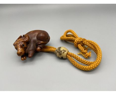 A Meiji period hand carved Japanese netsuke of an Ox laying down, Design with black bead eyes, signed by the artist. Also has