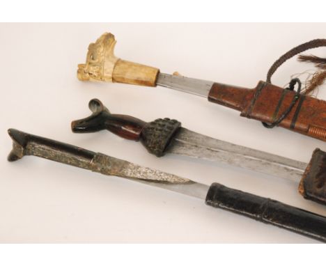 A Burmese machete with carved figural horn handle and wooden scabbard, together with two Indonesian short swords and scabbard