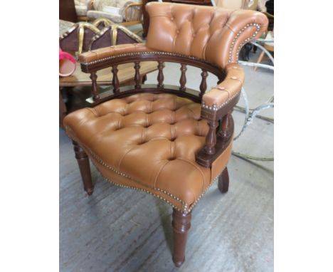 A button back captain's chair with a mahogany frame & tan leather upholstery