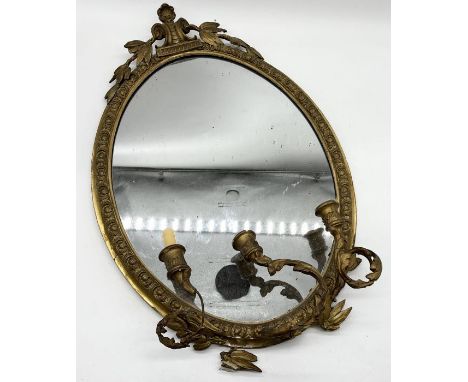 An antique gilt oval mirror with three branch candelabra and foliate decoration