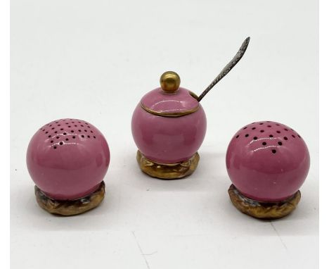 An early 20th Century Royal Worcester pink glazed globular three piece cruet set each piece raised on gilt basket weave foot,