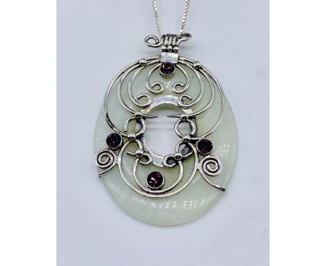 A large jade pendant mounted and decorated with silver