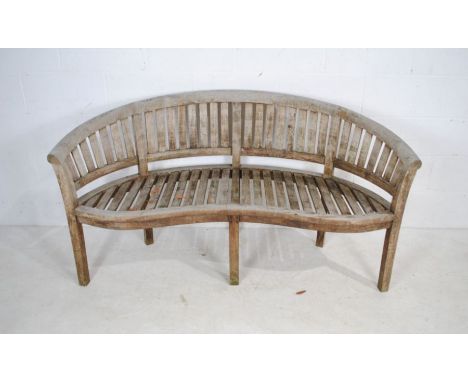 A weathered curved wooden garden bench - length 157cm