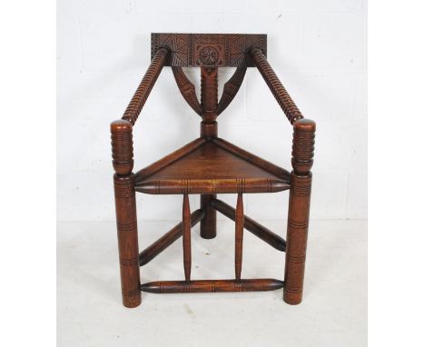 A 19th century Turner style chair with triangular solid seat, bobbin turned supports and carved detailing