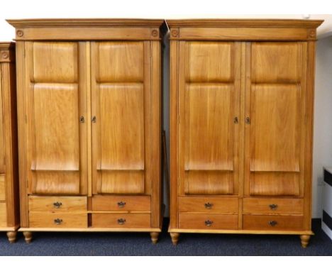 PAIR OF LIGHT MAHOGANY WARDROBES
with a shaped and moulded cornice above flower head motifs with a pair of shaped panel doors