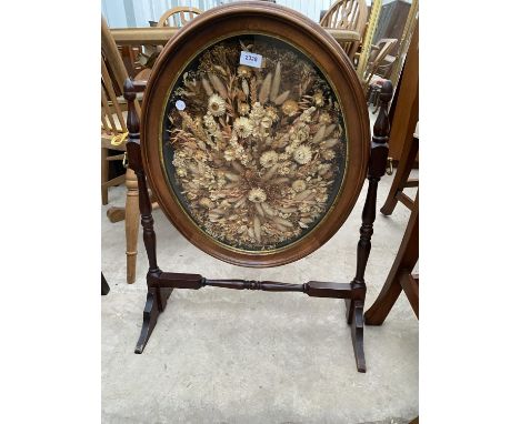 A VICTORIAN STYLE FIRESCREEN, THE OVAL SWING FRAME DECORATED WITH DRIED FLOWERS 