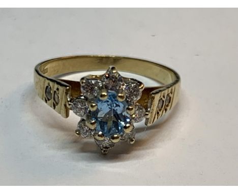 A 9 CARAT GOLD RING WITH A BLUE TOPAZ SURROUNDED BY CUBIC ZIRCONIAS SIZE K/L 