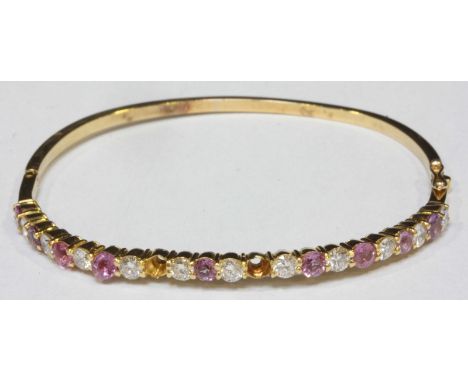 A David Morris 18ct yellow gold, diamond and pink sapphire hinged bangle, claw-set with 11-RBC diamonds estimated 1.10cts, an