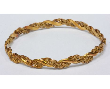 A yellow metal bangle of twist and plaited design, (tested as 18ct or higher), 6cm diameter, 13.99 grams