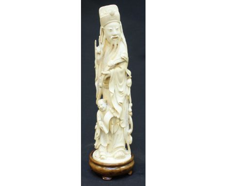 A Qing Dynasty carved Chinese ivory figure of Fuxing modelled wearing robes and holding a Ruyi with a child at his feet holdi