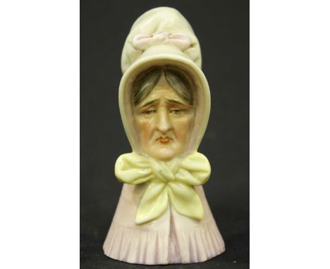 A 19th century Royal Worcester Porcelain candle snuffer modelled as an old lady wearing a white bonnet with pink ribbon, pink