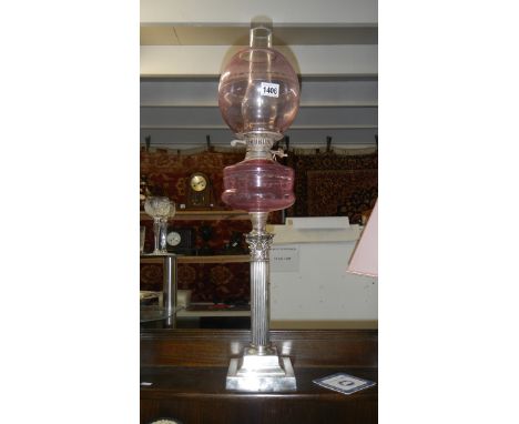 A silver plated Corinthian column oil lamp with cranberry glass font and shade