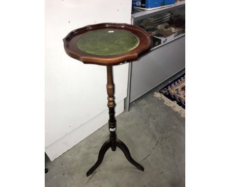A mahogany torchere on tripod feet and with leather inset top