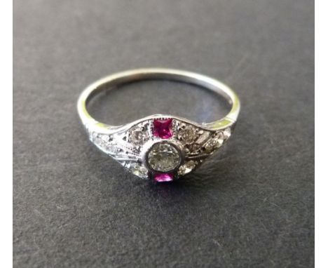 An 18ct. White Gold Ruby and Diamond Ring set with a central diamond flanked by diamonds and rubies