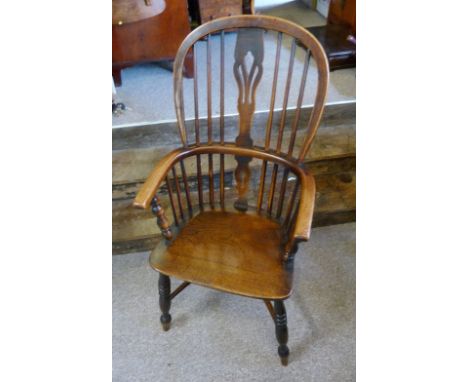 An Early 19th Century Elm Windsor Armchair, with a pierced splat and stick back above shaped arms with a panelled seat, raise