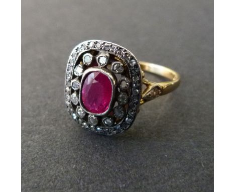 An 18ct. Yellow Gold Ruby and Diamond Ring set with an oval ruby surrounded by diamonds and with diamond shoulders