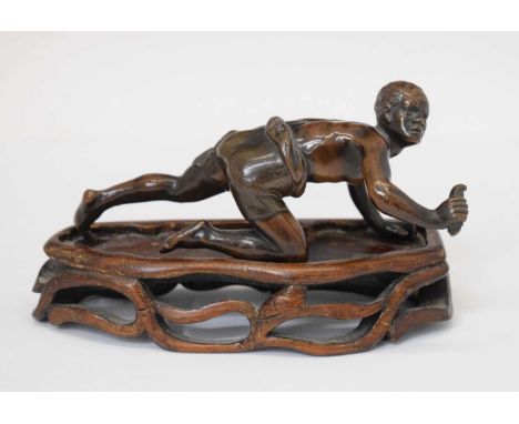 Bronze of crawling African figure hunting, with wooden stand, 13cm long 