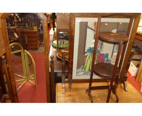 A 1930s oak cheval mirror, together with an oak and wool work inset folding fire screen occasional table, and a two-tier cake