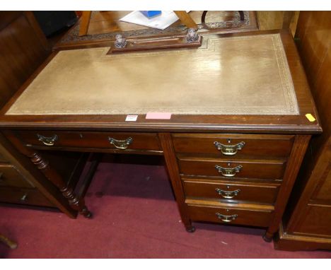 An Edwardian mahogany and gilt tooled tan leather inset kneehole writing desk, having an arrangement of five drawers and on t