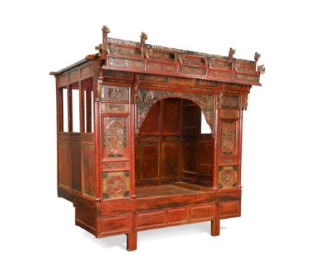 A Chinese red lacquer and painted bed, early to mid 20th century,with a carved pediment of flowers and birds and front panels