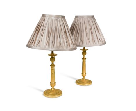 A pair of Regency engine turned ormolu candlestick lamps, circa 1820,with modern conversion to electricity 50cm high includin