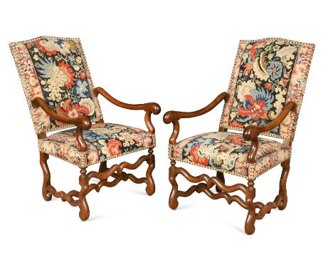 A pair of walnut framed high-back armchairs, 17th century,with tapestry upholstery and long arms, on scrolling legs, joined b