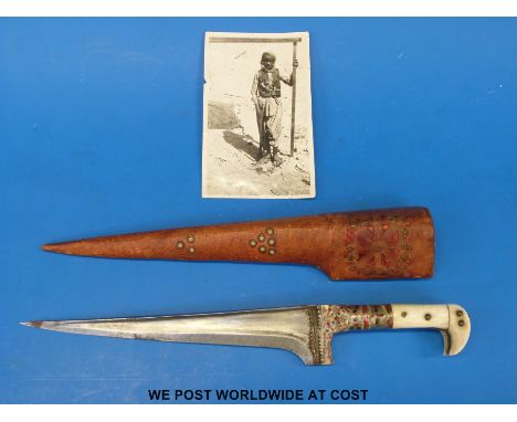 A Pesh Kabz dagger with bone and ivory grip, steel blade and leather scabbard together with a photograph featuring a similar 