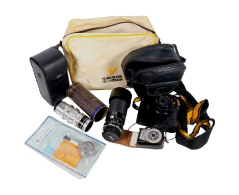 A group of cameras and accessories, including a Nikon EM camera with a Nikon lens Series E 50mm lens and soft case, a Tamron 