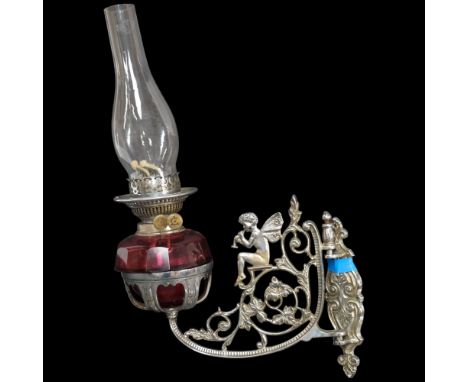 A 1930s cast and pierced chromed wall fitting oil lamp with cranberry glass bowl