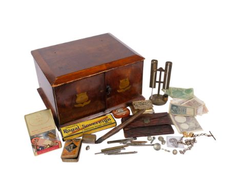 A table-top cabinet of 2 drawers, with brass shield motifs, 33.5cm across, and a tray with pencils, thermometer, stamp box, e