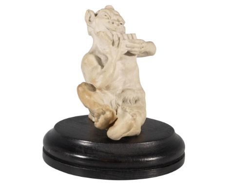 Stoneware modelled seated creature playing the pan pipes in a matt white glaze. Placed on a wood base. Incised Martin Bros, L