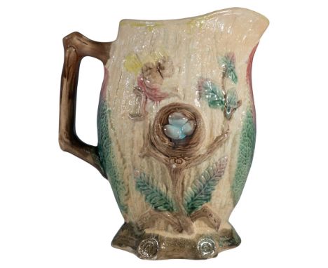 An enchanting pitcher designed to resemble a naturalistic tree trunk, featuring a small colorful bird tending to its nest wit