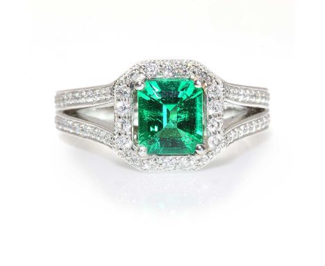 A platinum Columbian emerald and diamond hexagonal cluster ring,with an emerald cut Columbian emerald with a stated weight of