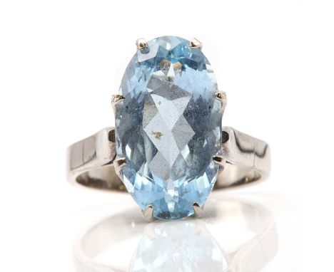 A single stone aquamarine ring,with an oval mixed cut aquamarine, claw set to a tapered pierced collet. Open flat shoulders t