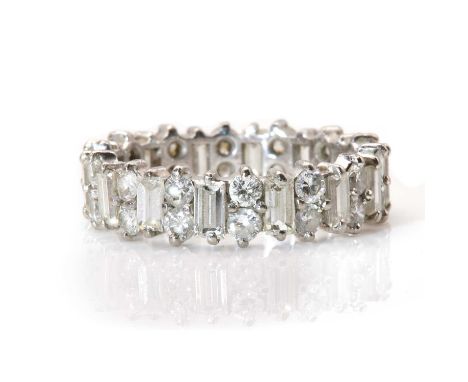 A white gold diamond full eternity ring,a continuous row of baguette cut diamonds alternating with pairs of brilliant cut dia