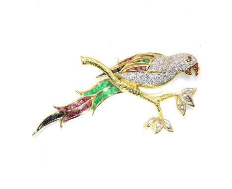 A gold diamond and gem set bird brooch, in the form of a parrot, perched atop a branch. The parrot with brilliant cut diamond