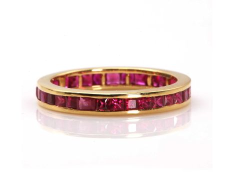 An 18ct gold ruby full eternity ring,with a row of calibré square and princess cut rubies, with a stated total weight of 2.32