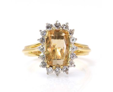 An 18ct two colour gold topaz and diamond cluster ring, by Boodle and Dunthorne, c.1980,with a cushion shaped mixed cut topaz