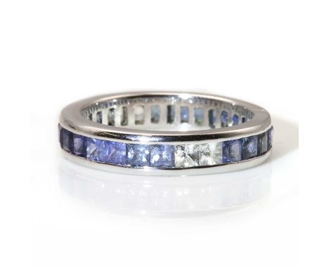 An ombré sapphire set full eternity ring,with a row of calibré cut sapphires, arranged from near colourless, through pale blu