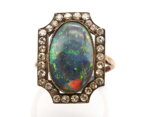 An Art Deco black opal and diamond plaque ring,with an oval cabochon black opal, milligrain set to a shallow collet. An open 