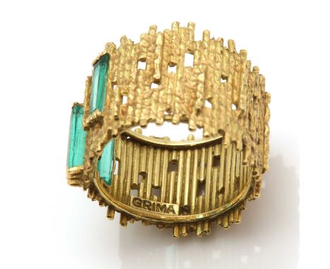 An 18ct gold emerald ring, by Andrew Grima, c.1960,with three elongated trap cut emeralds, end set in a staggered position. A