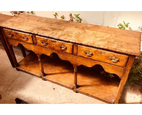 A George III revival oak dresser base utilising older timbers, rectangular top fitted with three frieze drawers on fluted sup