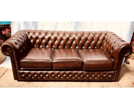 A 20th Century dark brown leather chesterfield two seater sofa, raised on bun feet.&nbsp;