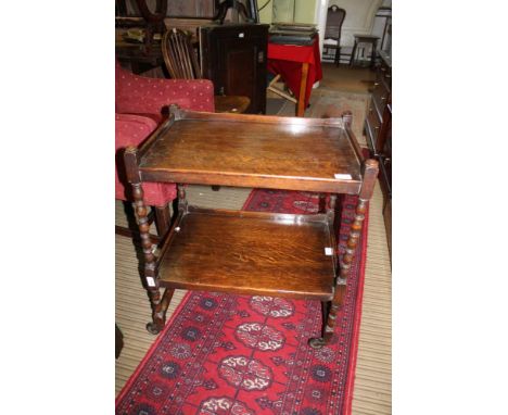 AN OAK TWO-TIER TEA TROLLEY with bobbin turned uprights 