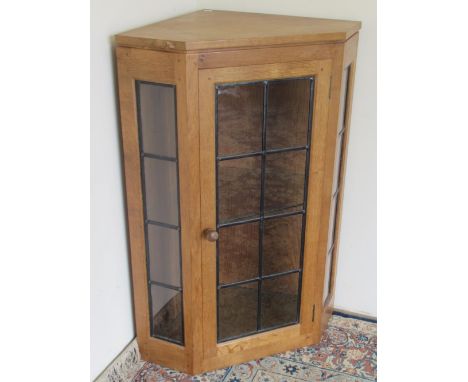 Robert Mouseman Thompson of Kilburn - an oak corner cabinet, with lead glazed side panels and door, carved with signature mou