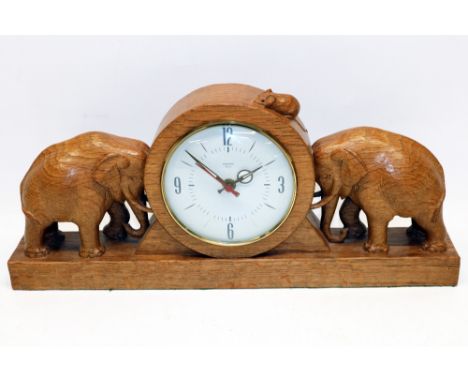 Robert Mouseman Thompson of Kilburn - oak mantel clock, with circular dial and two elephants on a plinth base, carved with si